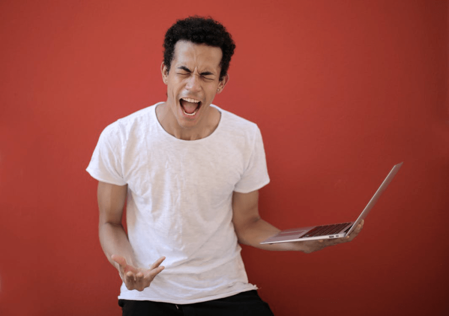 young male with laptop screaming